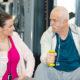 happy physiotherapist assisting senior man in lifting dumbbells